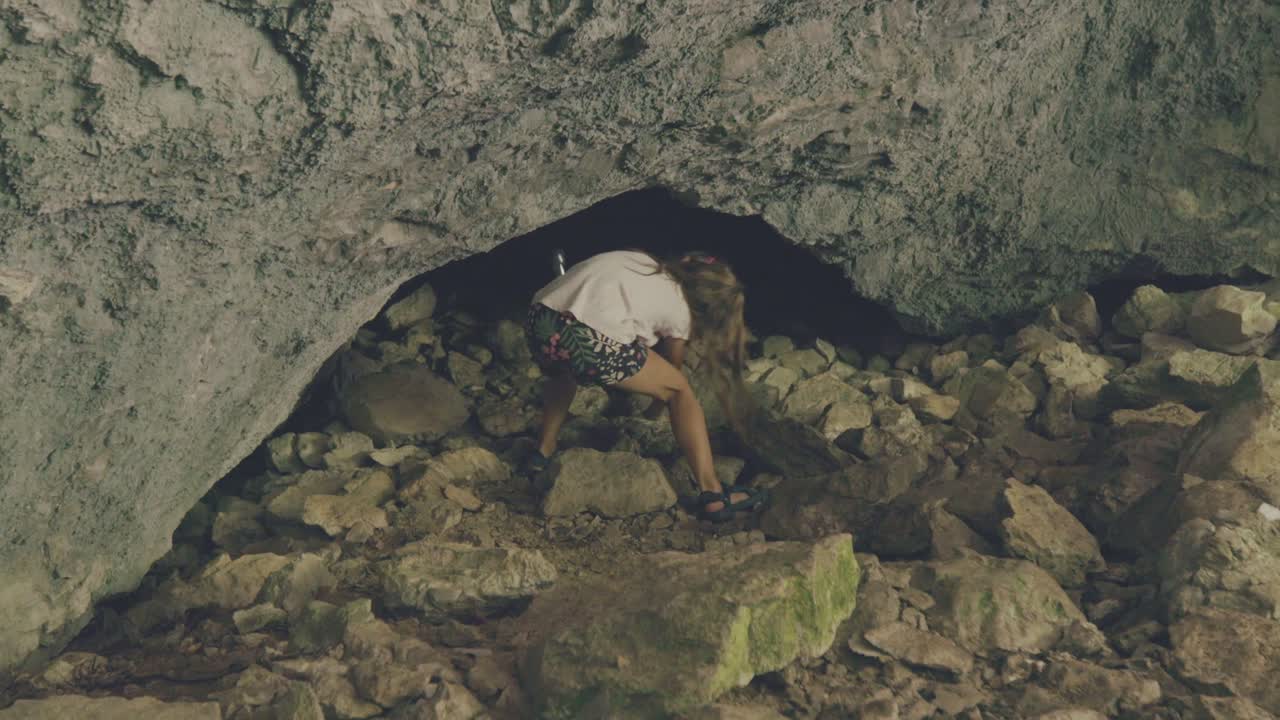 niña joven con linterna entrando en una cueva - toma de mano