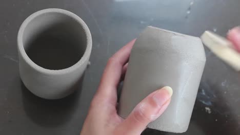 female potter artist in the final stages of smoothing and shaping surface of pottery cup with a wet sponge tool