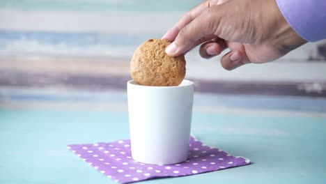 hand holding a cookie over a white cup