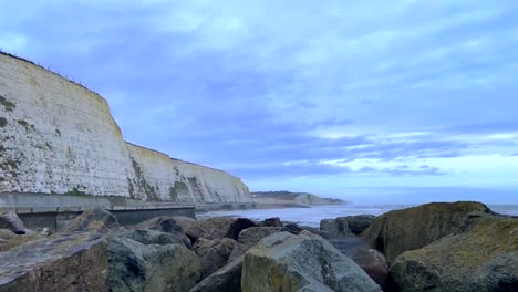 smooth right-tracking view over the rocks along the white cliffs of dover under a blue morning sky