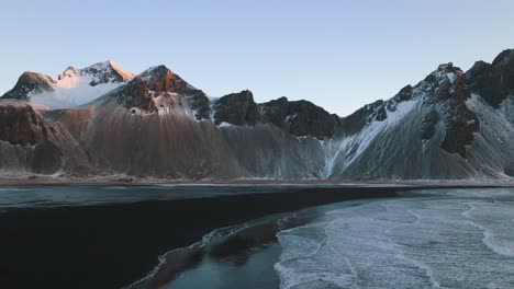 drone shot over the stokksnes black sand beach, sunny, winter evening in iceland