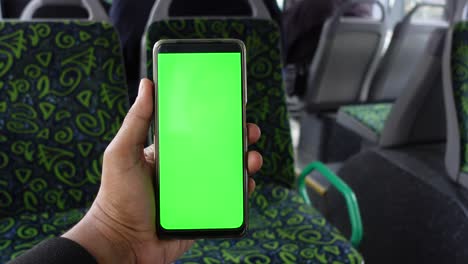 person holding a green screen phone on bus