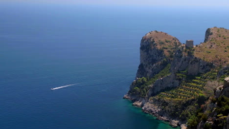 Rocky-Coastline-And-Turquoise-Sea-With-Boat-Going-By