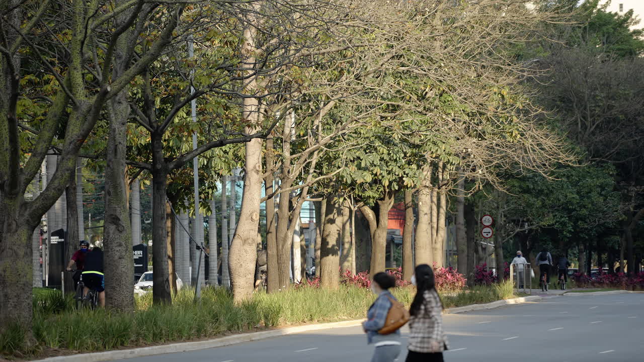 대도시의 분주한 거리 한가운데 자전거 도로를 달리는 자전거와 횡단보도를 건너는 사람들