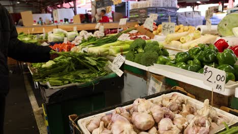 person selecting vegetables at market stall