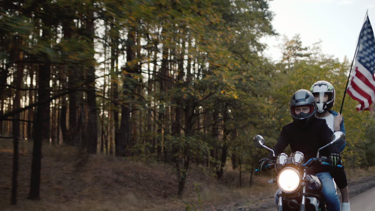 пара байкеров путешествует на мотоцикле, за которым следует американский флаг