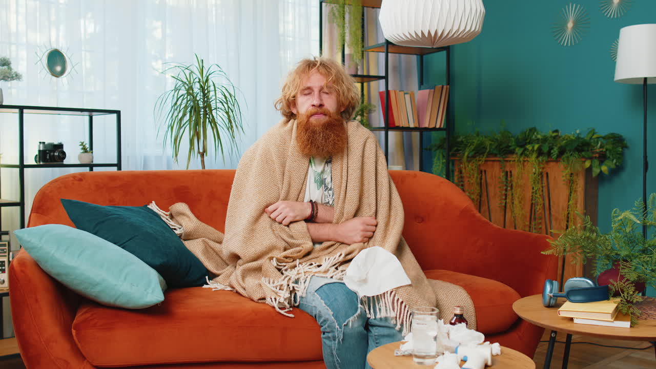 아픈 은 머리 남자가 감기나 알레르기를 고 집 소파에 누워서 재채기를 하고 킨에 을 니다.