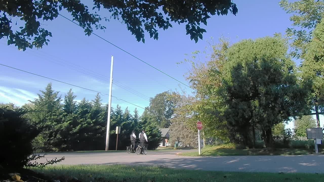 스쿠터를 타고 길을 내려가는 아미쉬 남자들