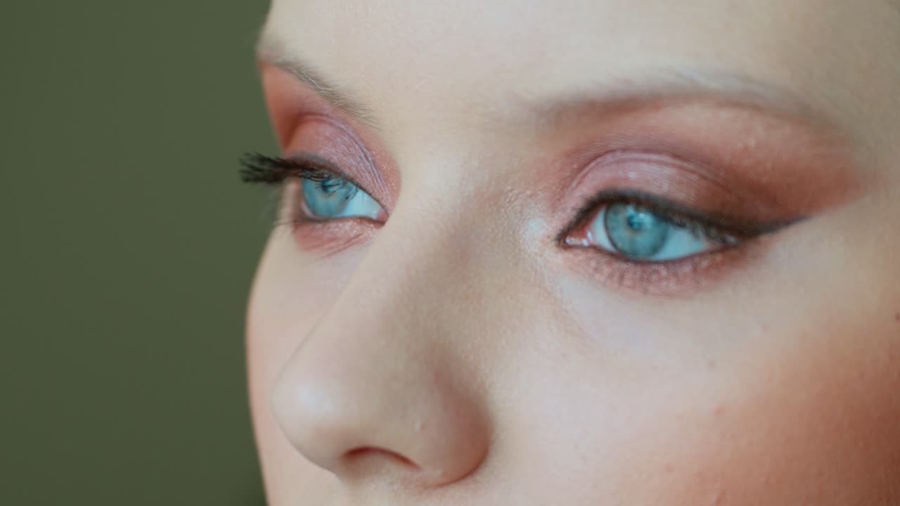 Close-up makeup application on a woman with blue eyes