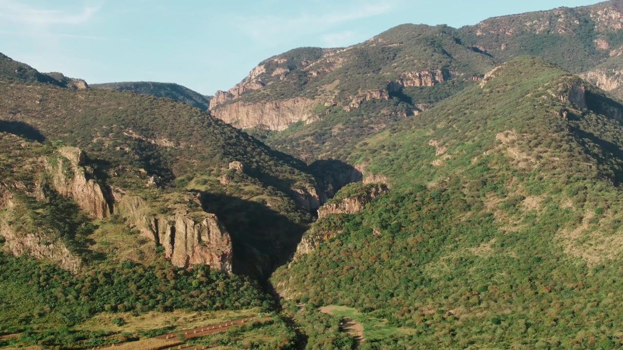 Ripresa aerea all'indietro sopra le scogliere del canyon, montagne verdi e campi della valle in Sierra Pénjamo, Guanajuato.