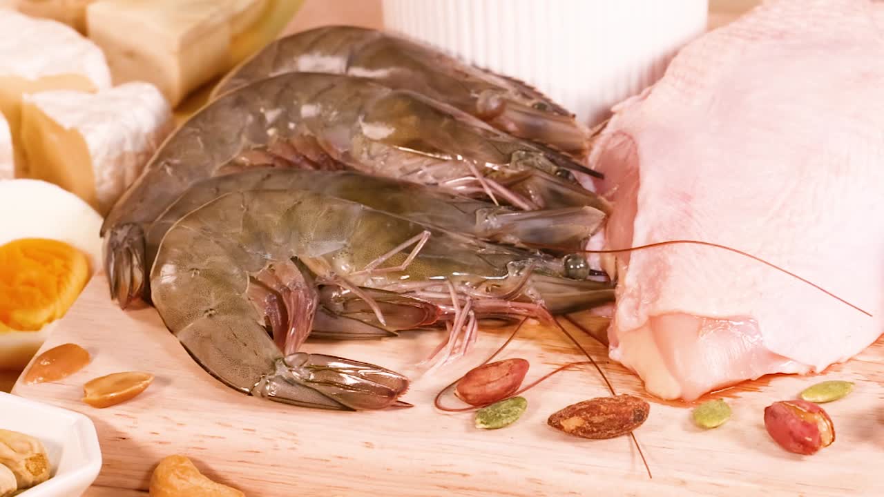 A selection of protein-rich foods including shrimp, meat, eggs, and various nuts displayed together.