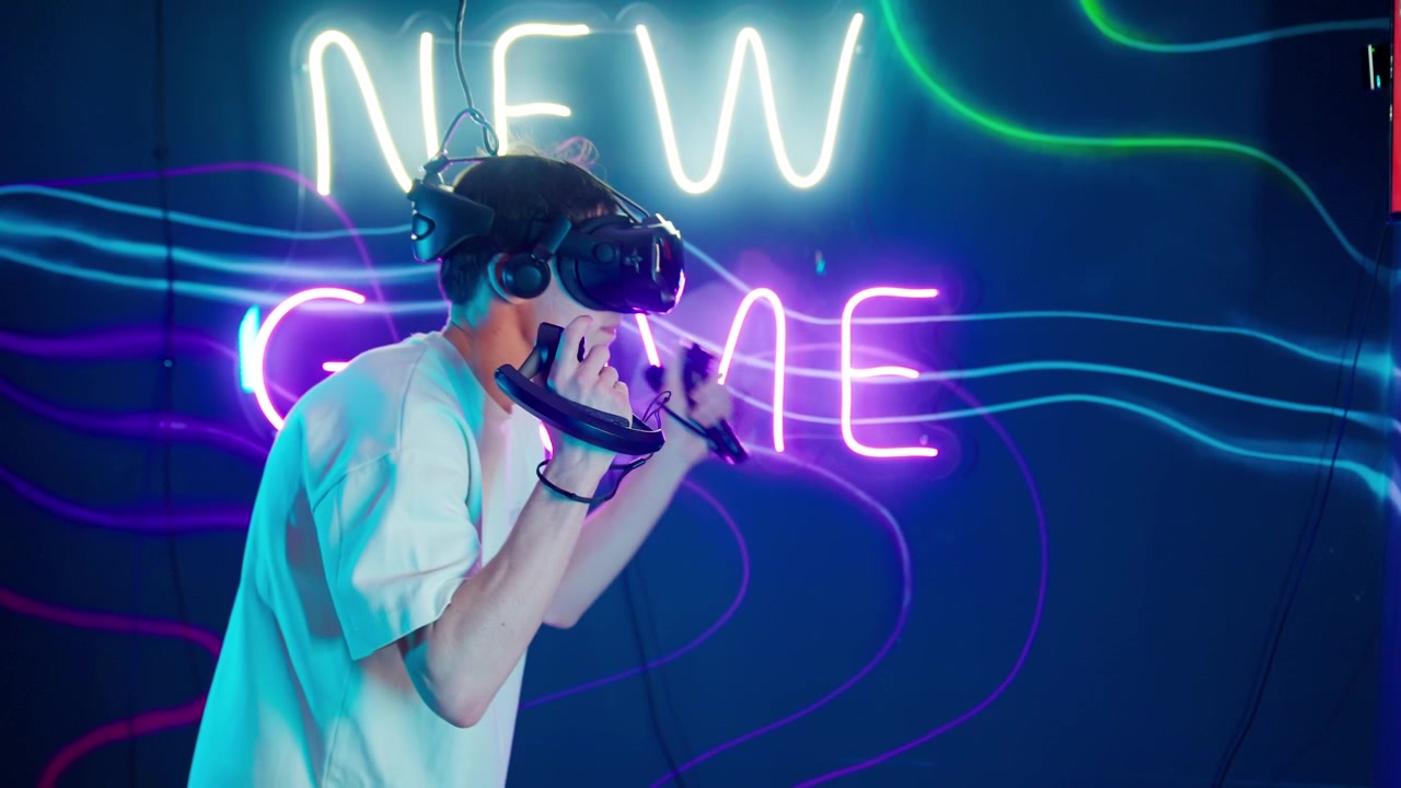 Giovane uomo che gioca a un gioco di realtà virtuale in una stanza illuminata al neon