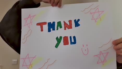 older student holding up thank you sign during video lecture