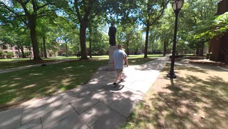 man left to right walking by statue 4k