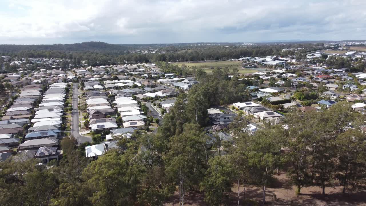 avión no tripulado volando sobre un barrio residencial de suburbio verde revelando casas privadas y paneles solares en muchas casas