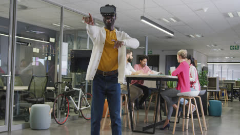 happy african american businessman using vr headset over colleagues in office