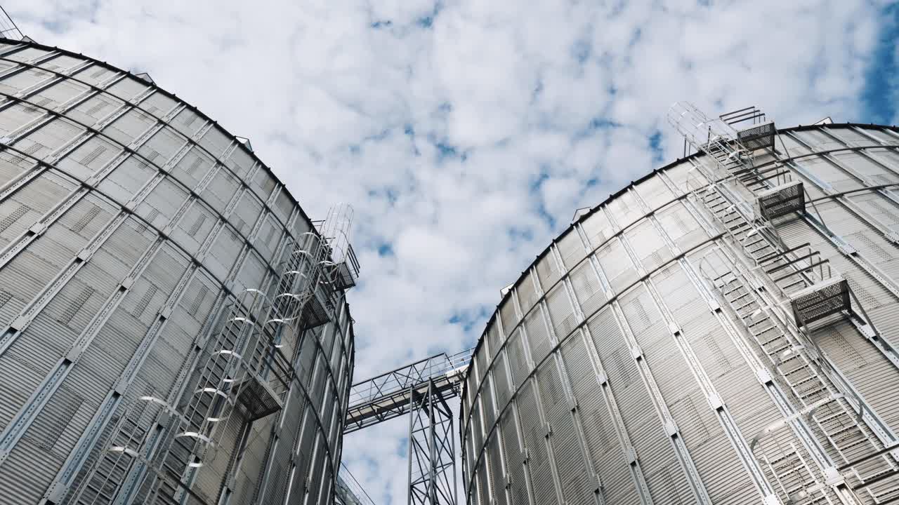 Silver silos against the sky background. Large grain elevators in a sunny day. Modern agriculture granary. Large hangars for storing crop