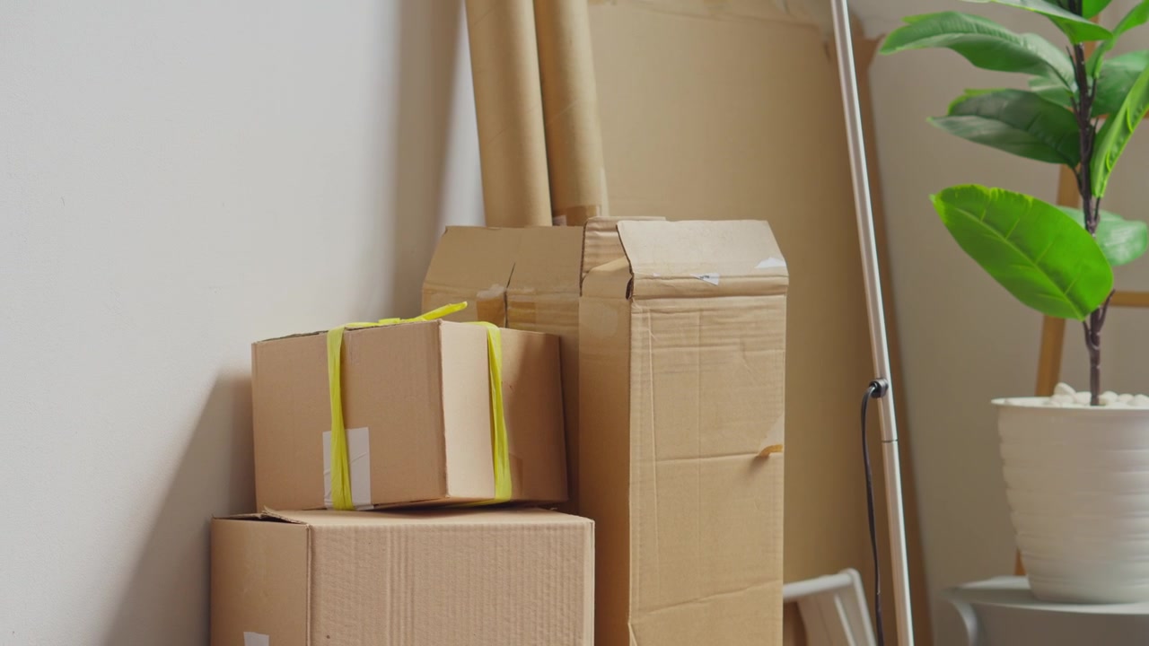 Cardboard boxes and moving supplies neatly stacked against wall in new home