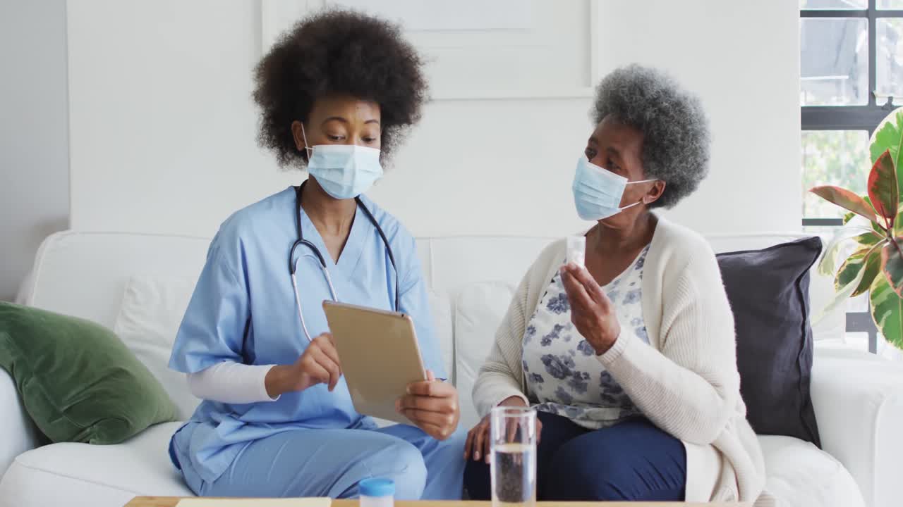 Femme médecin afro-américaine et patiente âgée portant des masques de protection.