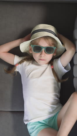 toddler boy plays with airplane while elder sister rests on couch near tourist suitcase. siblings relax on summer vacation upper close view