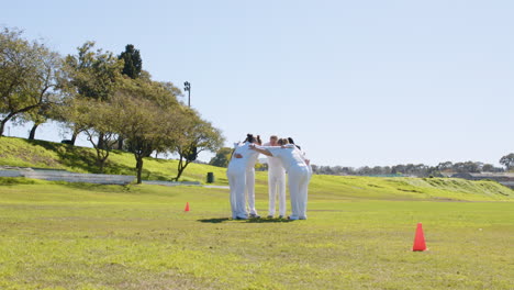 huddling together, female cricket team preparing for match on field
