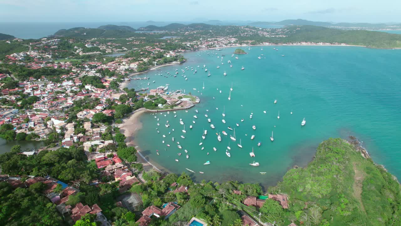 Paesaggio panoramico aereo con drone della spiaggia del mare blu di Praia dos Ossos, Búzios, baia tropicale, vegetazione e barche attraccate a Rio de Janeiro, Brasile