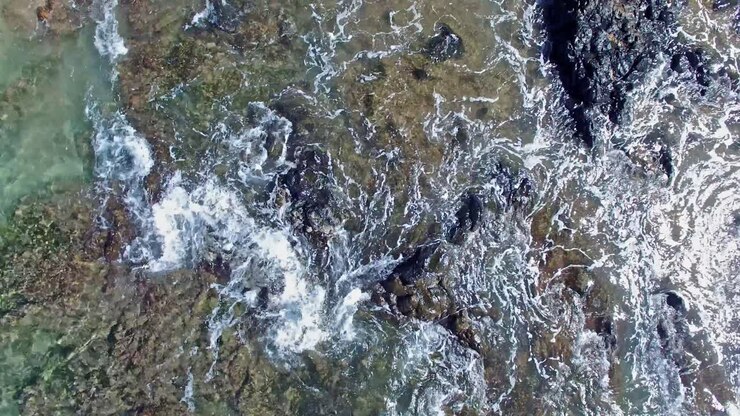 Ripresa aerea verticale dall'alto dell'acqua che scorre dentro e fuori dalla barriera corallina.