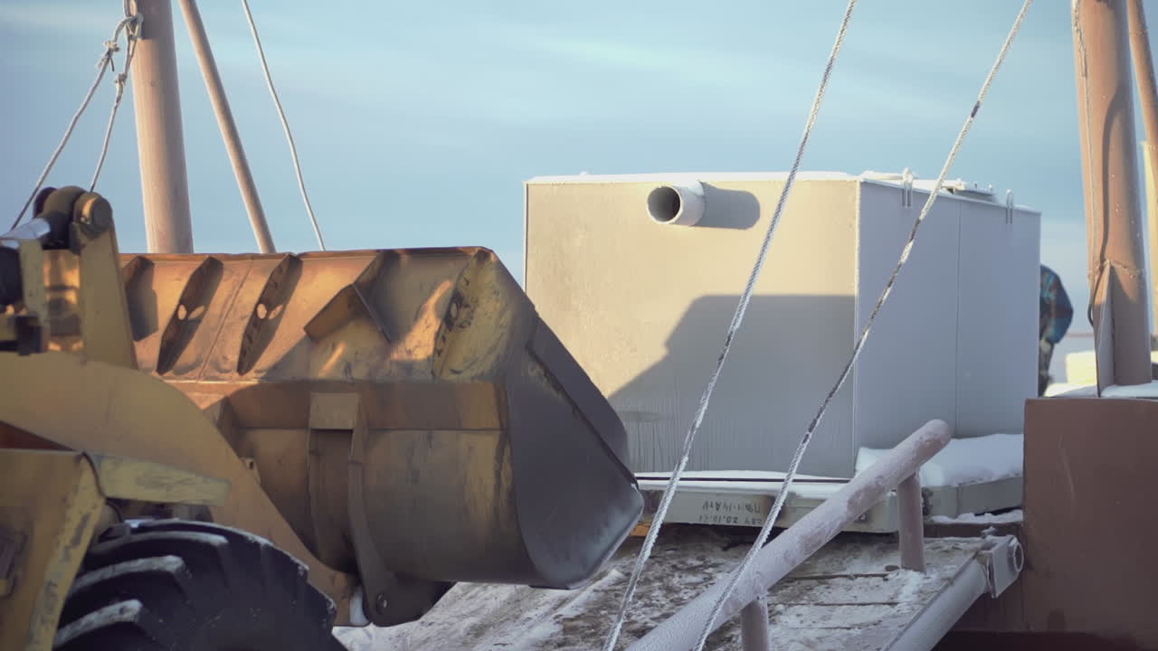 excavadora cargando un tanque en un remolque en invierno