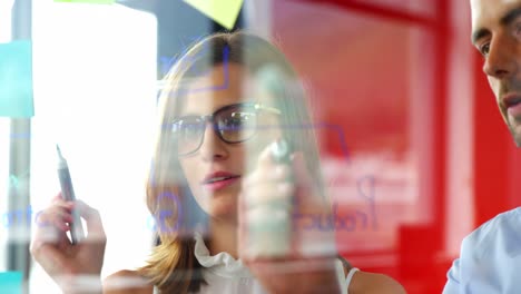 business executives writing on glass with marker