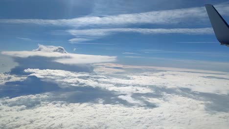 vista desde la ventana de un avión mirando desde arriba a las nubes con un cumulonimbus en un día soleado