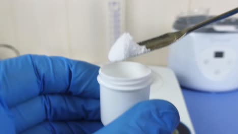 close-up of a laboratory technician's gloved hands performing a quality control test on hyaluronic acid powder in a cosmetic laboratory.