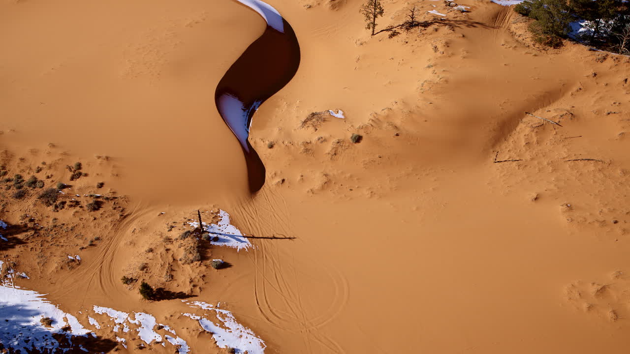 A breathtaking drone shot captures the vibrant hues and fascinating textures of the pink sand dunes.
