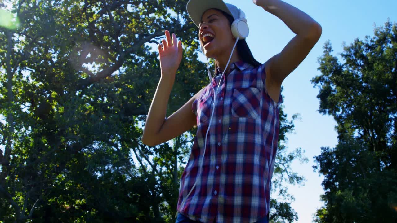 mujer bailando mientras escucha música en el parque 4k