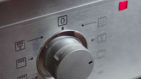 metallic toggle switch of the cooker oven close-up. front panel of modern oven. switching on the stove, baking oven and changing modes in order to preheat and cook meal