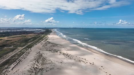 majestic wild sandy beach with near port of rotterdam, aerial view