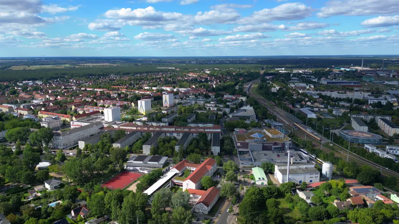 Hennigsdorf, Germany, showcasing residential areas, railway infrastructure and commercial buildings. Lovely aerial view flight ascending drone