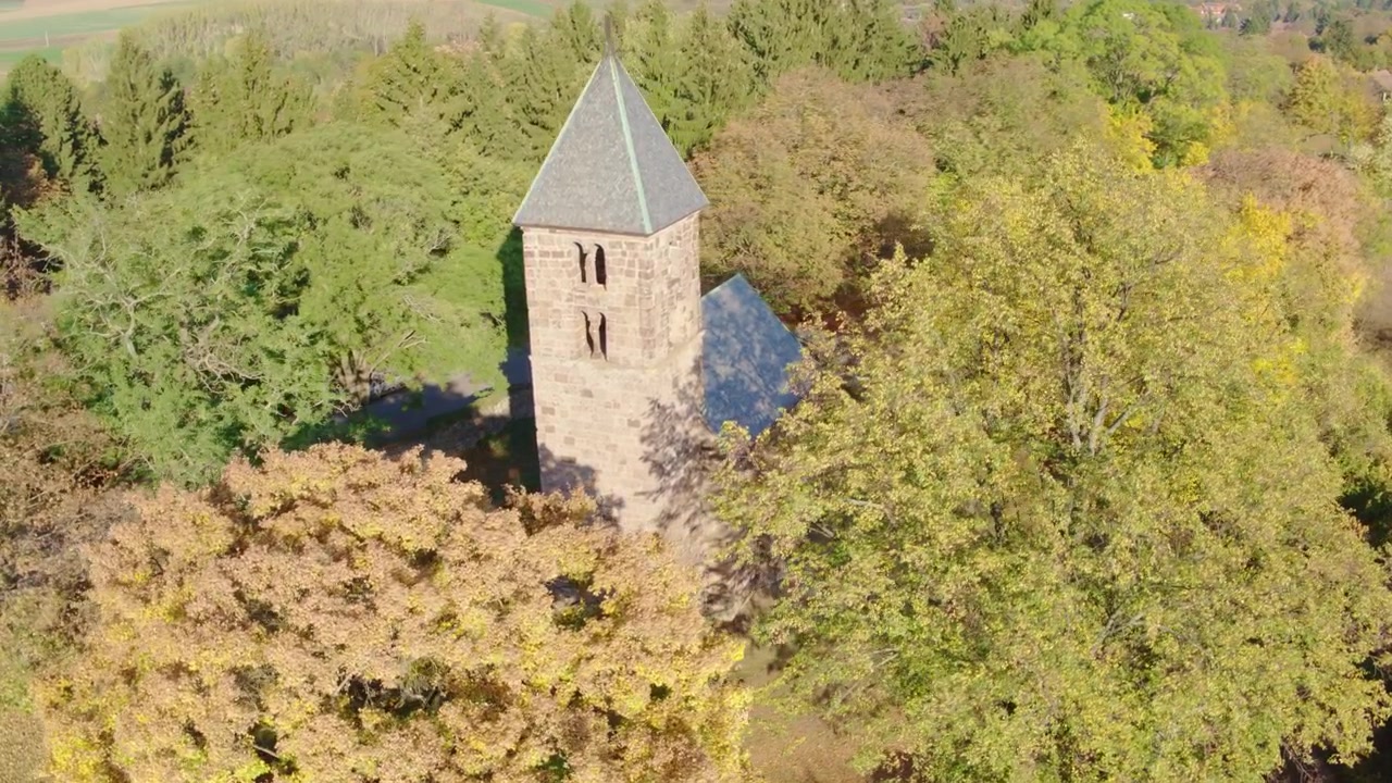 Luftaufnahme des Turms der St.-Stephans-Kirche, umgeben von Herbstbäumen