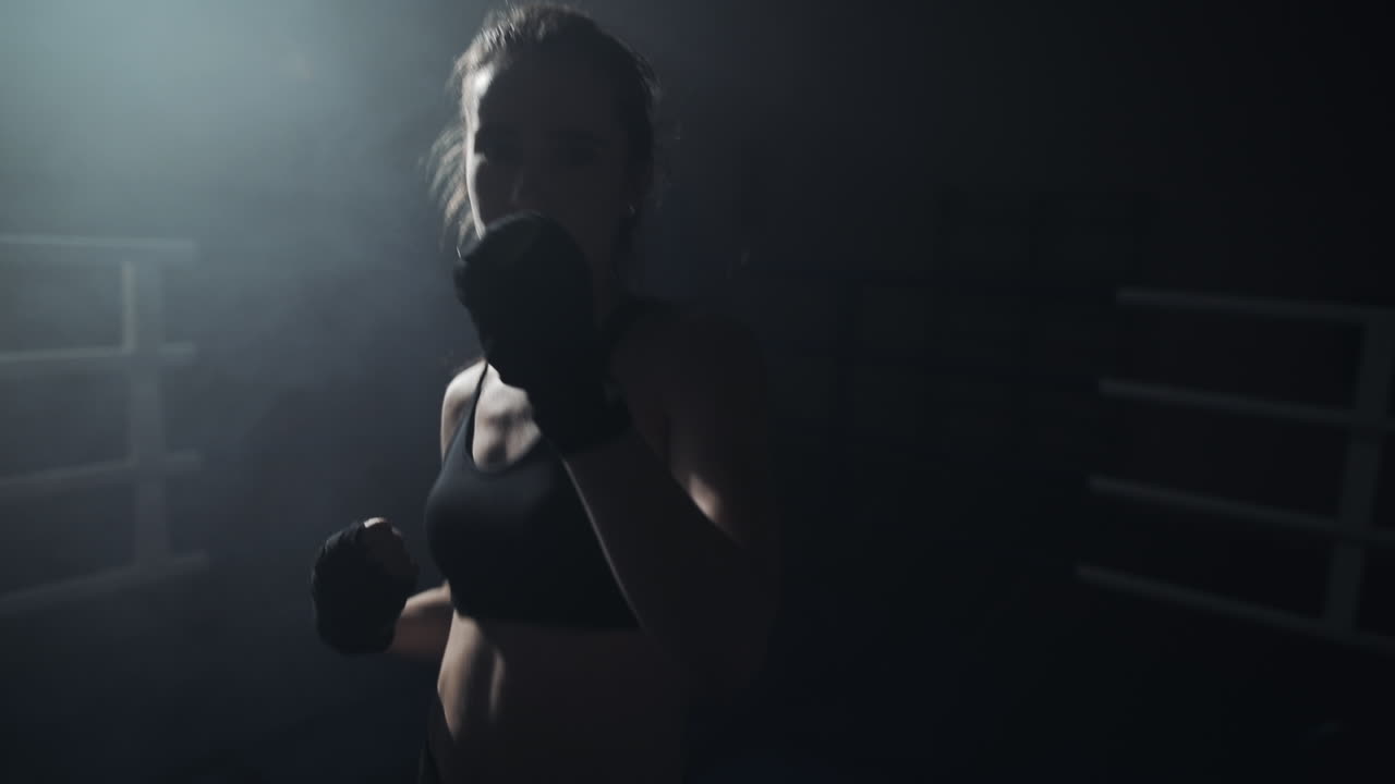 Female Boxer Training in a Dark, Smoky Ring