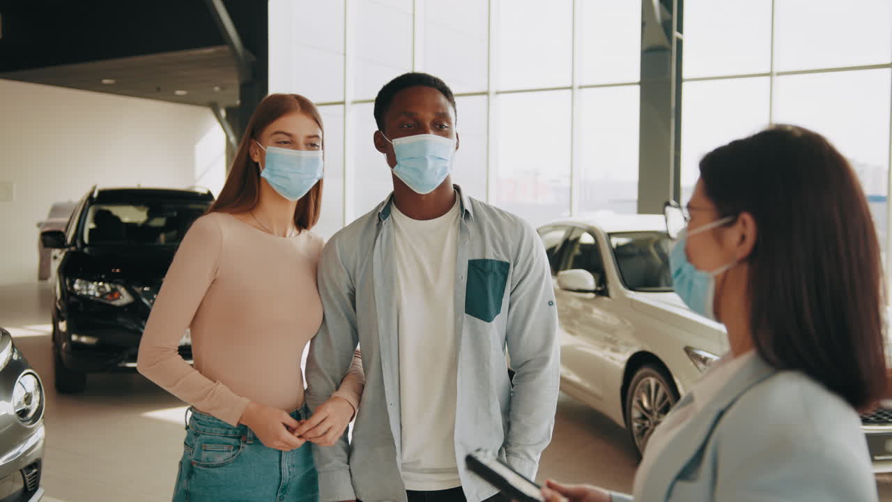 커플이 코로나19 기간 동안 대리점에서 자동차를 보고 있습니다.