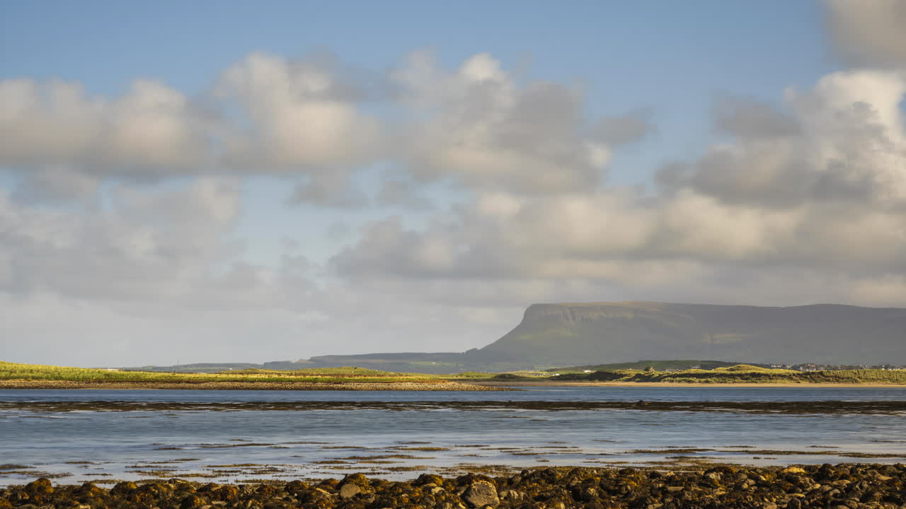 lapso de tiempo de la costa del mar de irlanda con colinas en la distancia y nubes en movimiento en el cielo