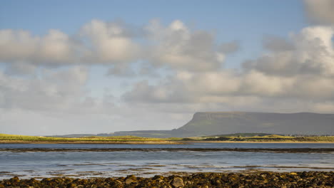 time lapse of sea coast of ireland with hills in the distance and moving clouds in the sky