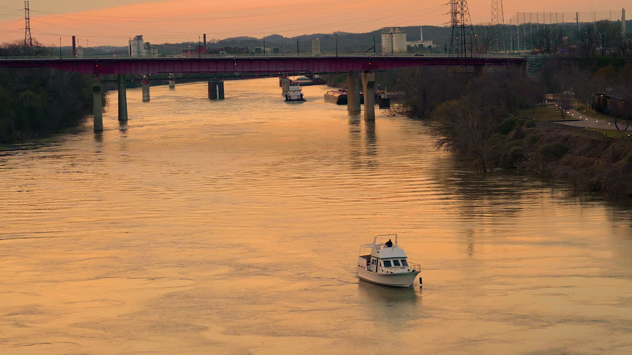 일몰 시간 동안 아름다운 황금 시간, 테네시 내쉬빌 시내에서 컴벌랜드 강으로 달리는 고급 보트가 물에 반사되어 있습니다.