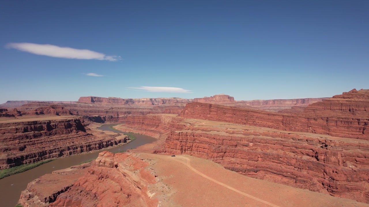 Drone che vola intorno a un fuoristrada parcheggiato sul bordo di una scogliera nel paesaggio di rocce rosse di Moab, USA, in 4K.