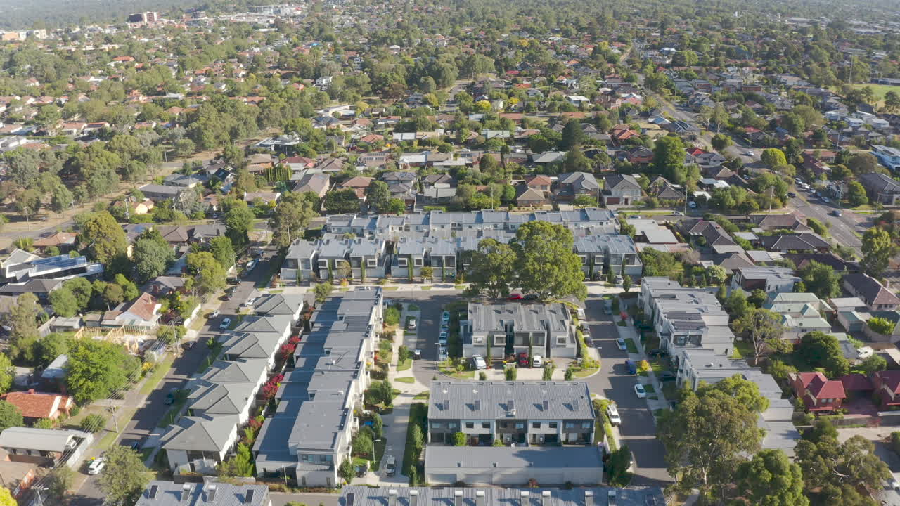 Aerial flyover of modern townhouses among existing neighborhood