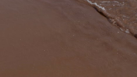 pei red sand beach with splashing water and seaweed
