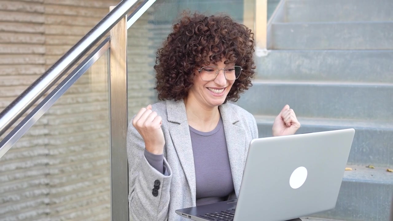 Una donna professionista dedita e concentrata intenta a lavorare al suo laptop all'aria aperta.