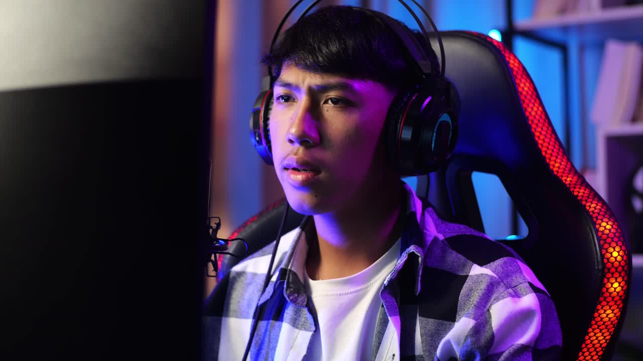 primer plano de un niño asiático jugando a un juego en red en una computadora personal. bostezando y durmiendo, videojuego de transmisión en vivo, escritorio iluminado por luz de tira led rgb