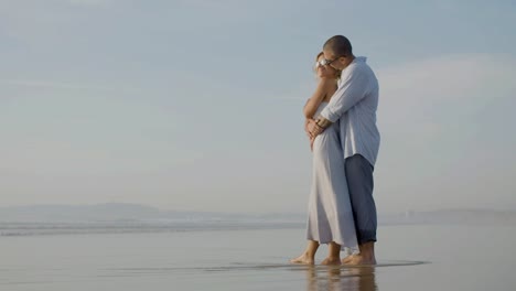 Feliz-Pareja-Caucásica-Con-Gafas-De-Sol-Viendo-La-Puesta-De-Sol-En-La-Orilla-Del-Mar