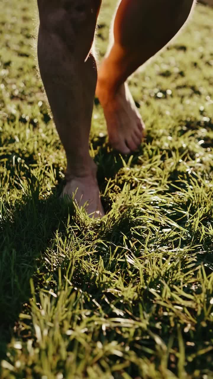 Close-up, low-angle shot of bare feet walking on grass, capturing a serene, natural vibe