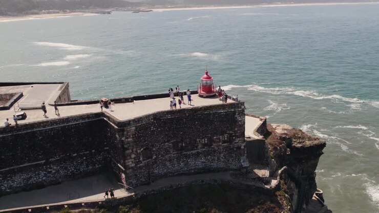 Vista panoramica aerea mozzafiato intorno al famoso faro di Farol da Nazaré sulla scogliera